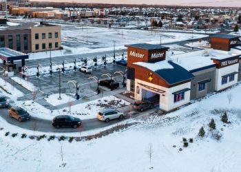 Aerial view of a line of vehicles at a Mister Car Wash location in a snowy suburban landscape