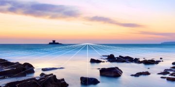 Jersey coastline at dusk, with a historic stone sea tower offshore and glowing white lines converging across the water toward the horizon