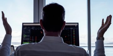 A investor at a desk with his hands raised on frustration