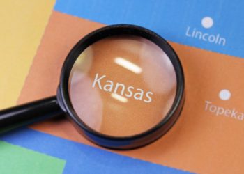 A magnifying glass focusing on the Kansas state map
